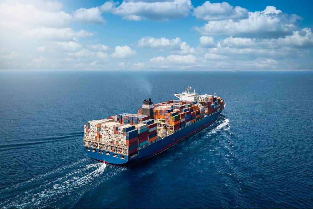 Cargo ship loaded with shipping containers on a calm blue sea.