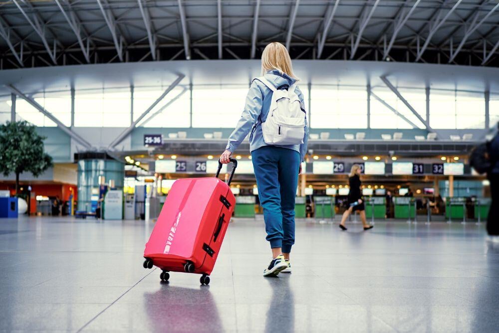 Woman with pink suitcase in airport.